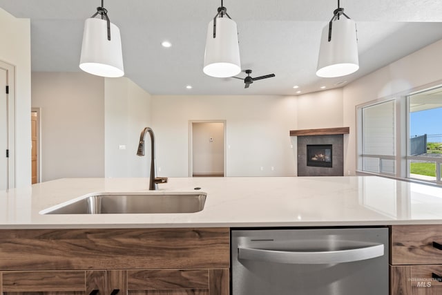 kitchen featuring hanging light fixtures, dishwasher, a fireplace, a sink, and open floor plan