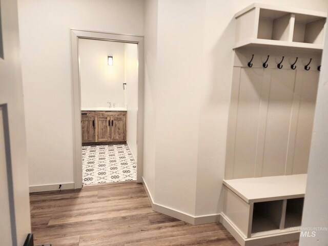 mudroom featuring a sink, wood finished floors, and baseboards