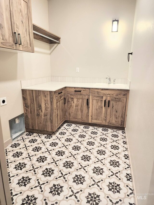 washroom featuring hookup for an electric dryer, baseboards, cabinet space, and a sink