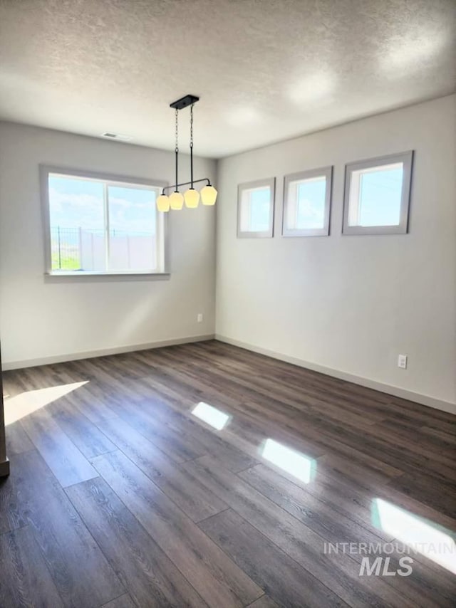 unfurnished room with a textured ceiling, dark wood-type flooring, and baseboards