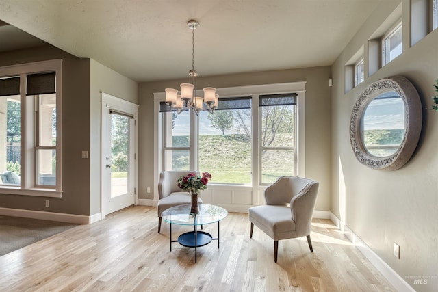 sitting room featuring light wood-style flooring, baseboards, and a chandelier
