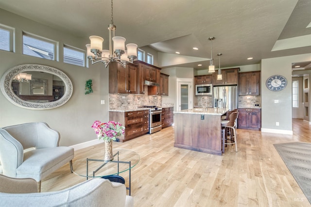 kitchen with stainless steel appliances, baseboards, a chandelier, a kitchen bar, and open floor plan