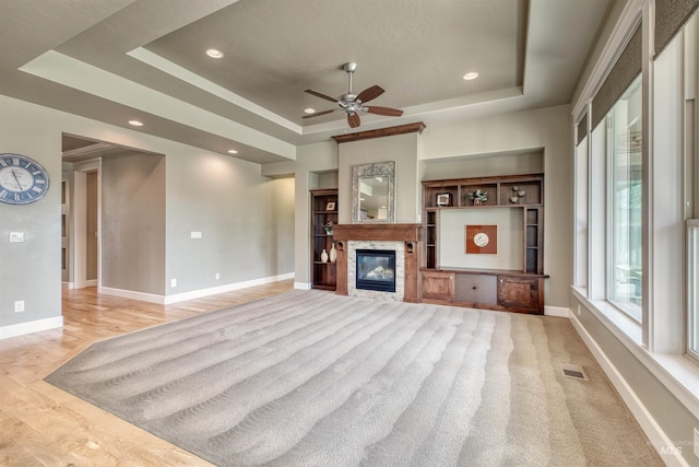 unfurnished living room with baseboards, a ceiling fan, visible vents, and a raised ceiling