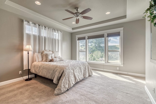 carpeted bedroom with recessed lighting, baseboards, and a raised ceiling