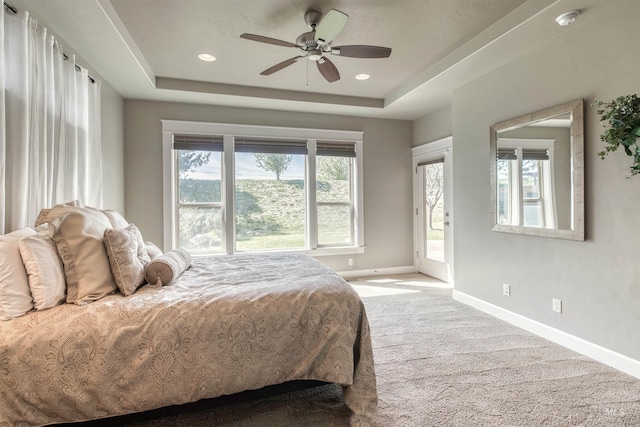 bedroom with a tray ceiling, carpet flooring, baseboards, and access to outside