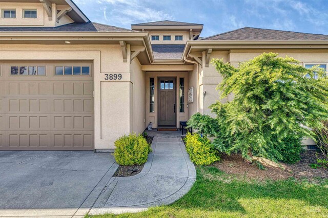 property entrance with an attached garage, concrete driveway, and stucco siding