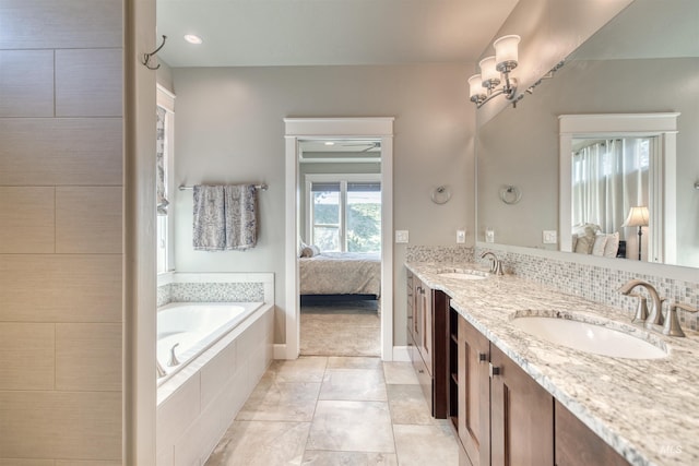 ensuite bathroom with a relaxing tiled tub, a sink, double vanity, and connected bathroom