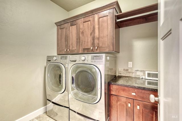 clothes washing area with cabinet space, baseboards, and washer and dryer