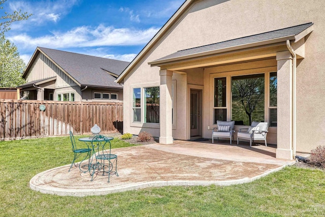 rear view of house featuring fence, a lawn, stucco siding, and a patio