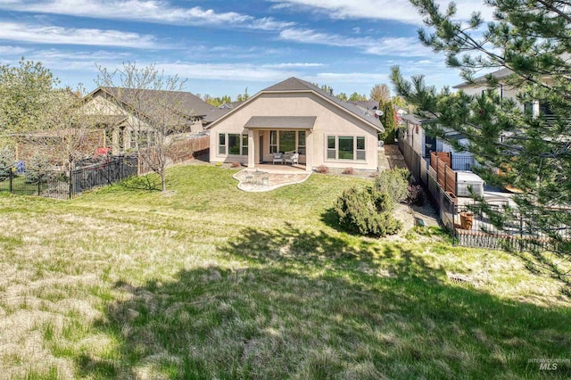 rear view of house featuring stucco siding, a yard, a patio, and a fenced backyard