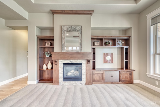 unfurnished living room with carpet floors, a glass covered fireplace, and baseboards