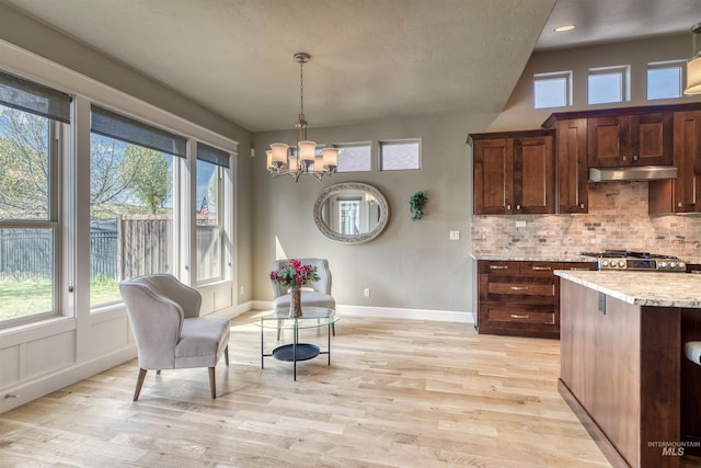 kitchen featuring a chandelier, light wood-style floors, a wealth of natural light, and under cabinet range hood