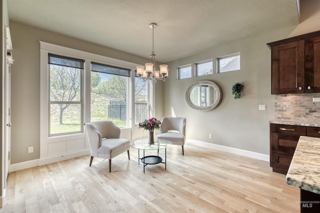 sitting room featuring baseboards, a wealth of natural light, a chandelier, and light wood-style flooring