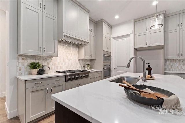 kitchen featuring gray cabinets, decorative light fixtures, sink, and stainless steel gas cooktop