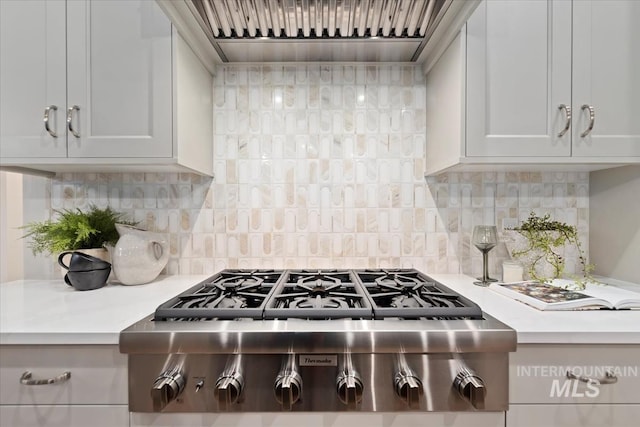 kitchen featuring stainless steel gas cooktop, backsplash, and wall chimney range hood