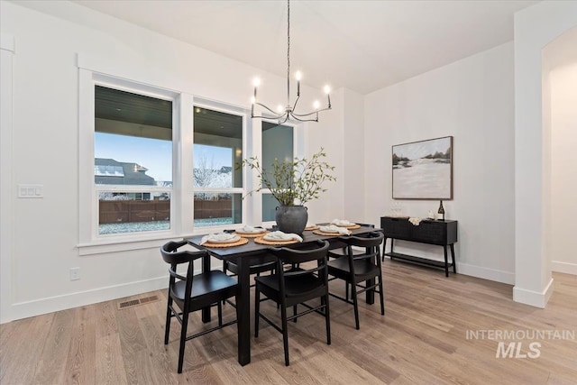 dining area with light hardwood / wood-style floors and a notable chandelier