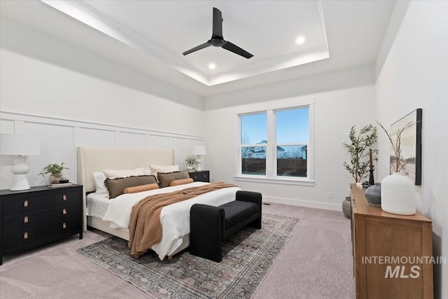 bedroom featuring a tray ceiling, ceiling fan, and light carpet