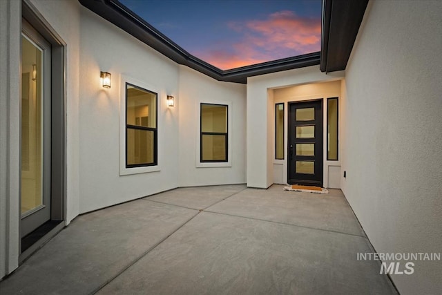 exterior entry at dusk featuring a patio area