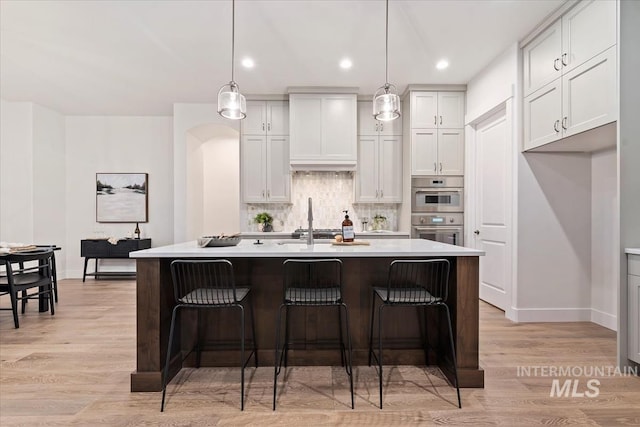 kitchen with a center island with sink, decorative light fixtures, and white cabinets