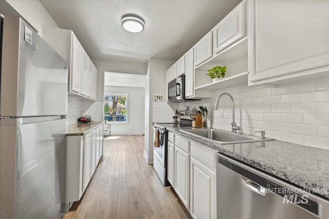 2706 W Ponderosa Rd, Boise, ID 83705 - kitchen with appliances with stainless steel finishes, tasteful backsplash, a sink, white cabinets, and light wood-style floors