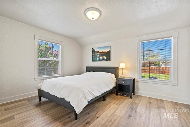 2706 W Ponderosa Rd, Boise, ID 83705 - bedroom featuring baseboards, lofted ceiling, multiple windows, and light wood-type flooring