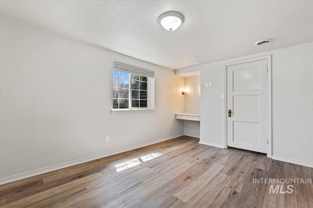 2706 W Ponderosa Rd, Boise, ID 83705 - unfurnished room featuring built in study area, baseboards, a textured ceiling, and wood finished floors