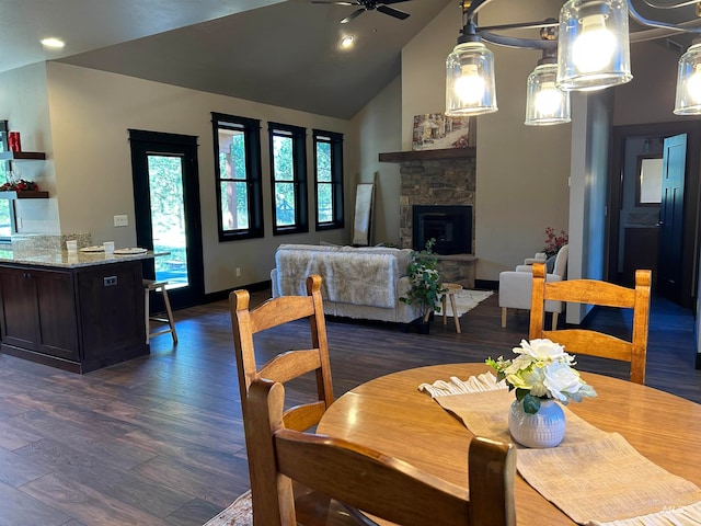 dining space featuring dark hardwood / wood-style flooring, ceiling fan, a fireplace, and vaulted ceiling