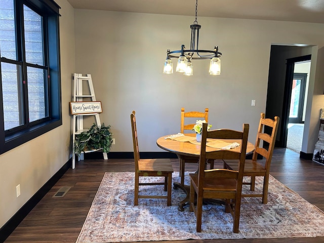 dining area featuring dark wood-type flooring and a chandelier