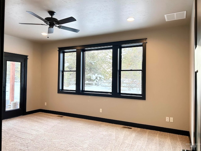 carpeted spare room featuring ceiling fan and a wealth of natural light