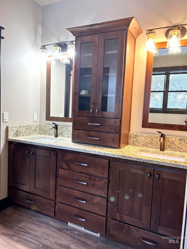 bathroom with dual bowl vanity and hardwood / wood-style flooring