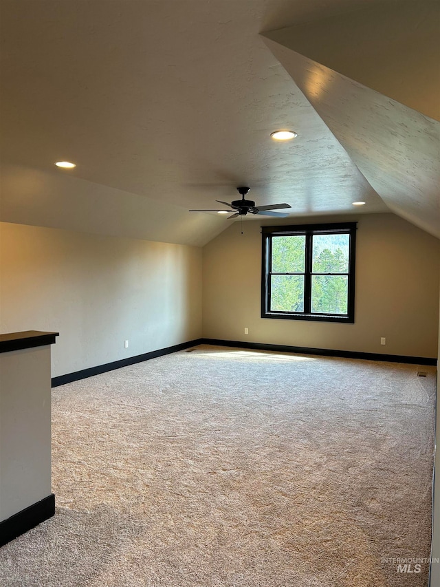 spare room with ceiling fan, vaulted ceiling, and carpet