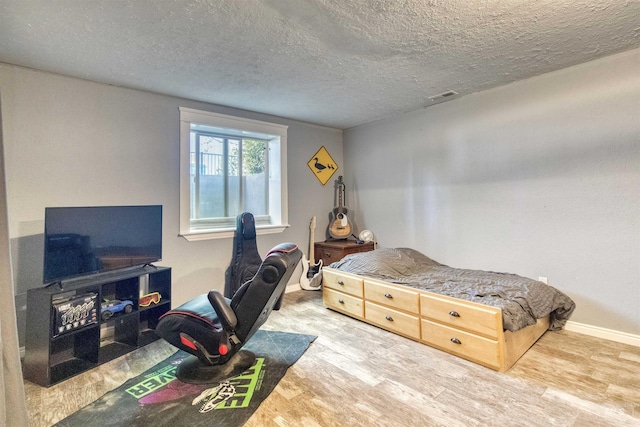 bedroom with a textured ceiling and hardwood / wood-style floors