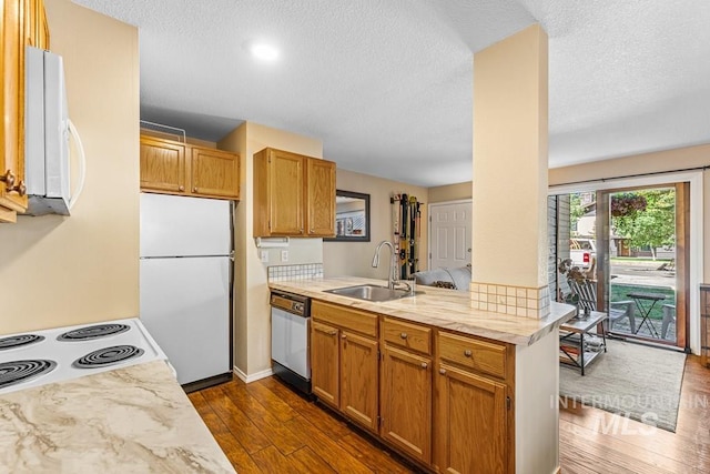 601 Hemlock St Unit 3, Mccall, ID 83638 - kitchen featuring white appliances, dark wood-style floors, a peninsula, a textured ceiling, and brown cabinets