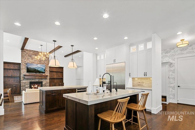 3345 W Dublin St, Eagle, ID 83616 - kitchen featuring an island with sink, a fireplace, glass insert cabinets, recessed lighting, and dark wood-type flooring