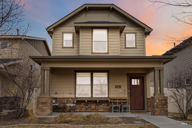 view of front of home with covered porch and stone siding