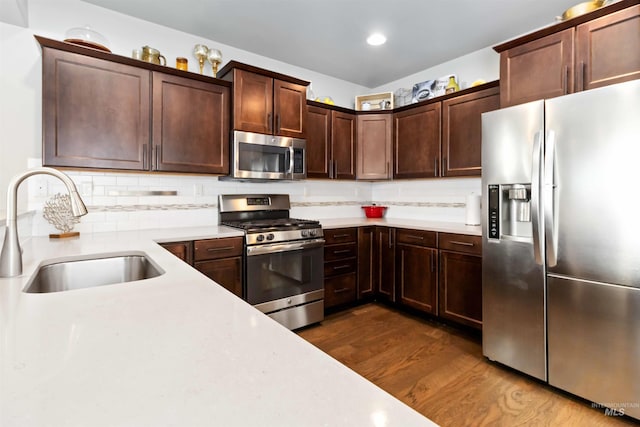 kitchen with light countertops, appliances with stainless steel finishes, dark wood-style flooring, and a sink