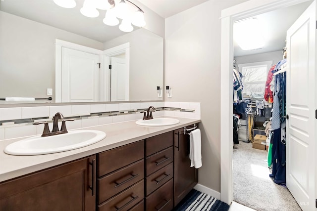 full bath with double vanity, tasteful backsplash, a sink, and a walk in closet