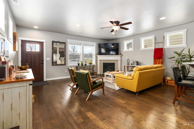 living room with baseboards, a glass covered fireplace, dark wood-style floors, ceiling fan, and recessed lighting