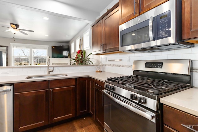 kitchen featuring dark wood-type flooring, a sink, light countertops, appliances with stainless steel finishes, and tasteful backsplash