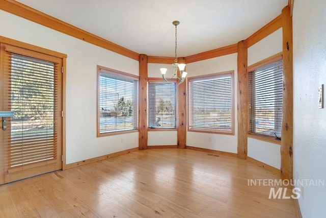 unfurnished dining area featuring light hardwood / wood-style floors, an inviting chandelier, and crown molding