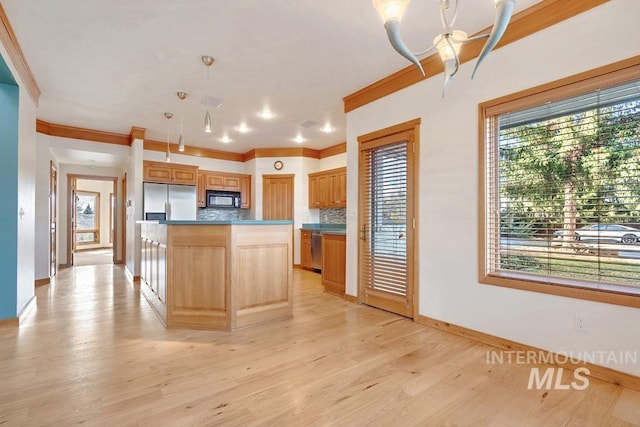 kitchen featuring a center island, tasteful backsplash, pendant lighting, a chandelier, and appliances with stainless steel finishes