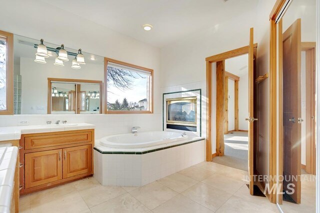 bathroom with tile patterned flooring, vanity, and tiled bath