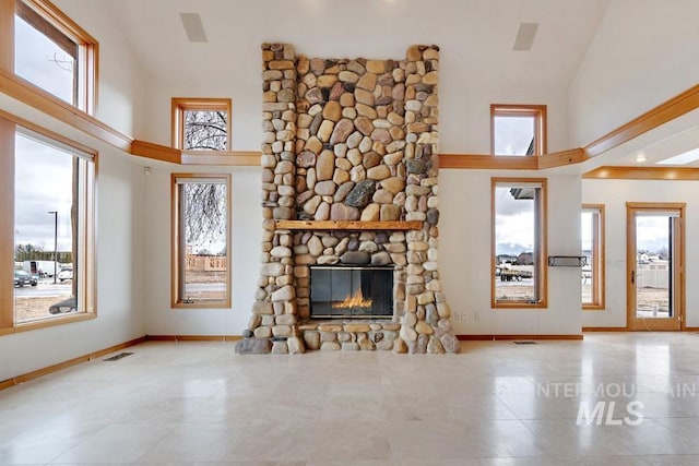 unfurnished living room featuring a stone fireplace and a high ceiling