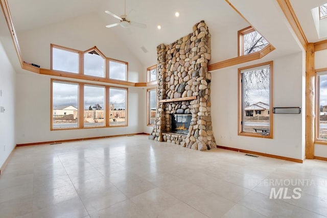 unfurnished living room with ceiling fan, a fireplace, and a towering ceiling