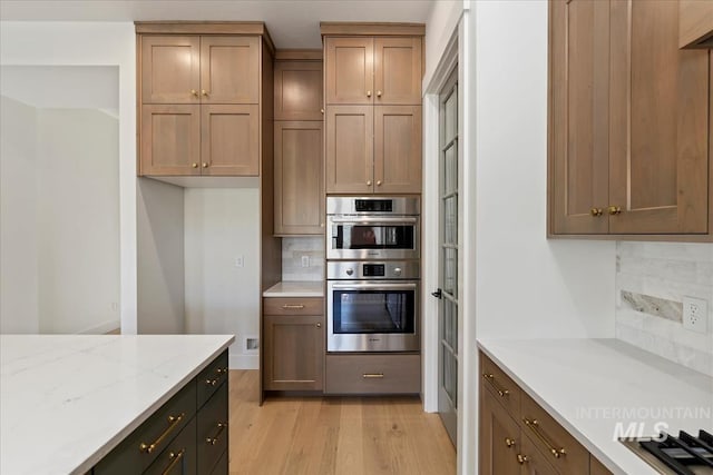 6535 S Evie Way, Eagle, ID 83714 - kitchen featuring light wood-type flooring, appliances with stainless steel finishes, light stone countertops, and tasteful backsplash