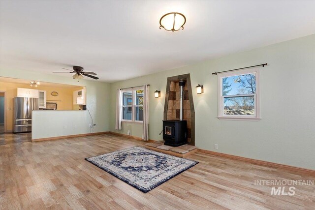 120 W Main St, Hagerman, ID 83332 - unfurnished living room featuring a wood stove, ceiling fan, and light hardwood / wood-style flooring