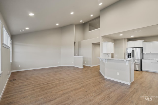 10449 W Thimbleberry Dr, Star, ID 83669 - kitchen with stainless steel fridge with ice dispenser, white cabinetry, a kitchen breakfast bar, light wood-style floors, and recessed lighting