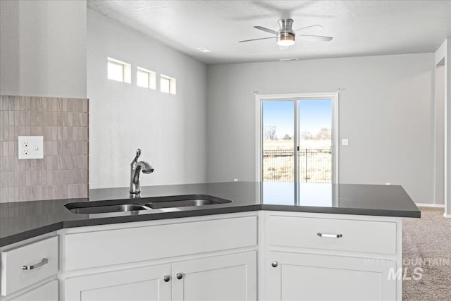 kitchen featuring sink, carpet flooring, kitchen peninsula, ceiling fan, and white cabinets