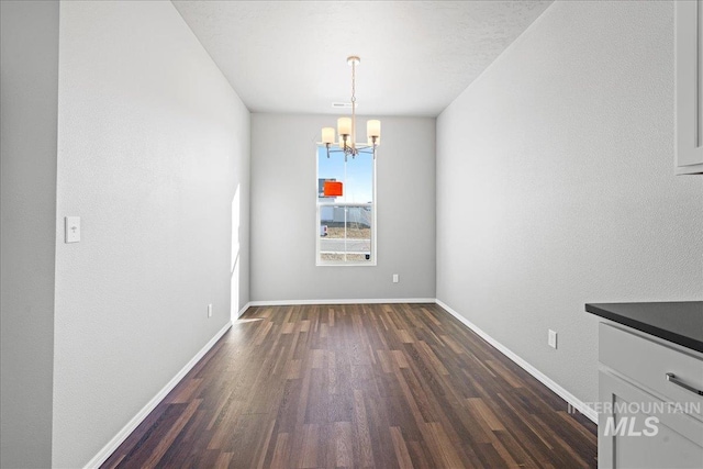 unfurnished dining area with a notable chandelier and dark hardwood / wood-style flooring