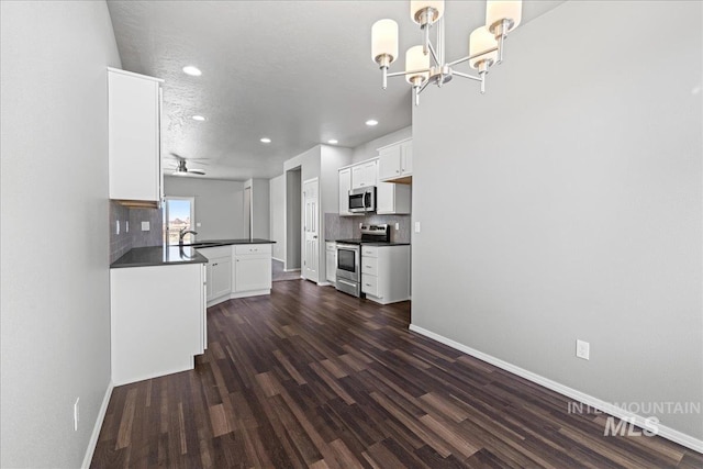 kitchen featuring appliances with stainless steel finishes, white cabinets, decorative backsplash, decorative light fixtures, and kitchen peninsula